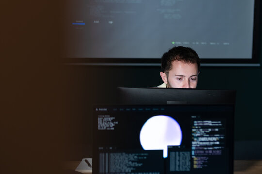 Male Computer Programmer working on Coding task, Concentration on computer monitor typing on keyboard, writing code for ai prompt, Software Application development sit at desk in office.
