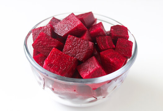 Fresh diced red beetroot cubes filled in a clear glass bowl on a white background.