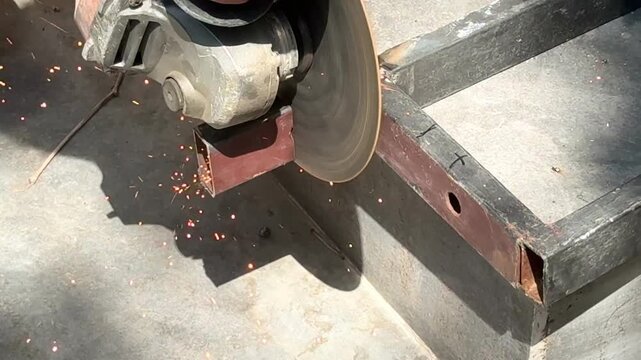 Angle grinder cutting metal profile pipe outdoors close up macro concept for construction work, DIY repair, metalworking tool, occupational health hazard workplace safety violation. 4k High quality