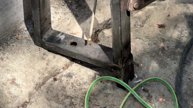 Welding electrode burning hole through thick metal pipe outdoors close up macro concept for arc cutting, metalworking technique, high temperature heat, fabrication. 4k High quality