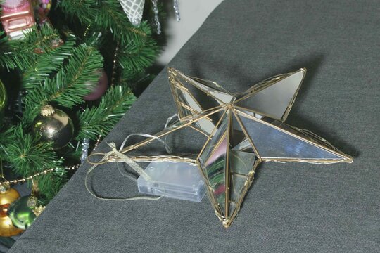 Star decoration placed on a table near a Christmas tree during the holiday season