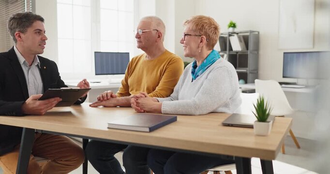 Senior couple advisor meeting for retirement consultation. Professional reviews agreement terms, noting investment options and planning to help the client. Clear trust finance concept icon.