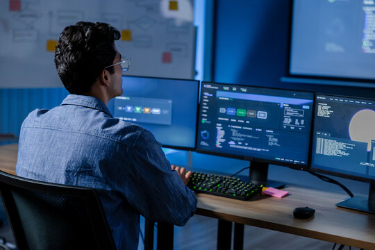 Machine learning engineer reviewing AI model dashboard and system performance at computer workstation while analyzing technical metrics, software status, data visualization and model results.