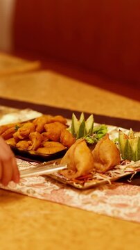 Serving Indian Samosas and Pakoras with Tongs in a Restaurant