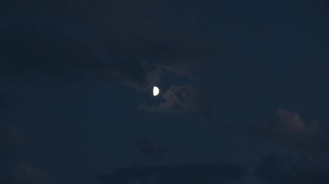 A glowing half moon in the dark and cloudy night