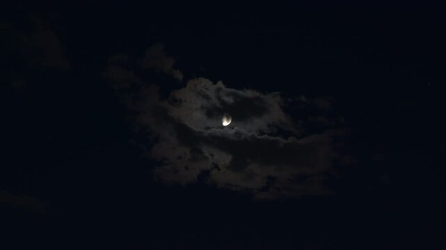 A glowing half moon in the dark and cloudy night