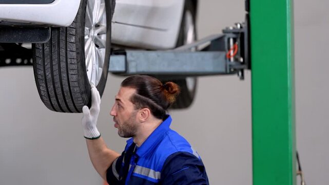 EV technician inspecting wheel and undercarriage during electric car maintenance in repair garage