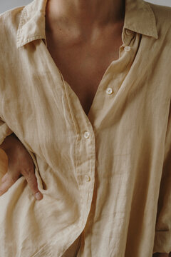 Close-Up Of Woman In Unbuttoned Beige Linen Shirt Posing With Hand On Hip