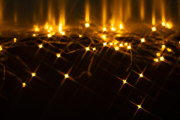 Fototapeta premium Golden starburst lights scattered across dark reflective surface with glowing trails for festive abstract background and overlay