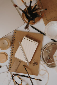 Flat Lay Composition Of Artist Desk Essentials Featuring Kraft Paper Journals, Pen, And Eyeglasses