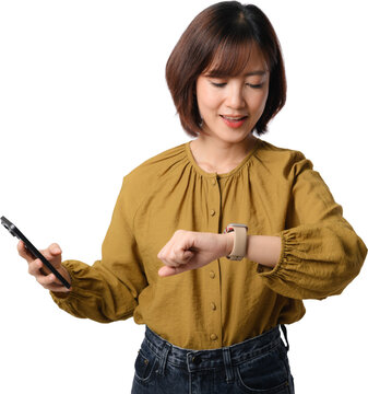 Happy asian woman checking smartwatch time holding mobile phone device with cheerful smile standing over transparent cutout background