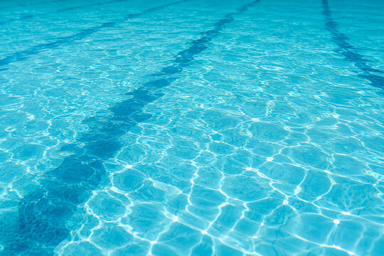 Clear blue swimming pool water surface with ripples and light reflections