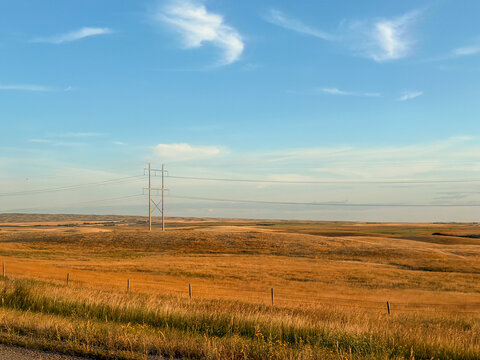 Golden prairie landscape with power line tower at sunset, Great Plains