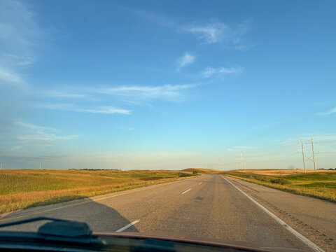 Driver point of view on rural two-lane highway through golden prairie landscape