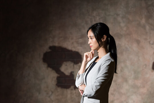 暗い部屋で考える女性。ビジネス、不安、心配、疑問、将来、落ち込む、転職、就職、仕事、困る、悩み、問題