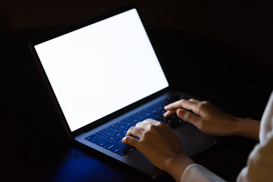A woman using a computer in a dark room. PC, dark, crime, crime prevention, security, risk, hacker, darkness, internet.