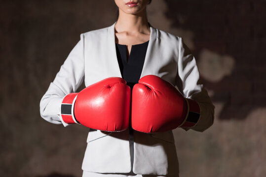 A businesswoman wearing boxing gloves and striking a fighting pose.