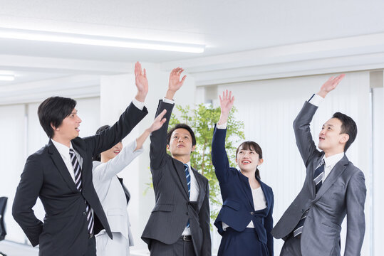団結するビジネスグループ。チームワーク、ハイタッチ、バンザイ、目標、達成、挑戦、成功、祝福、協力