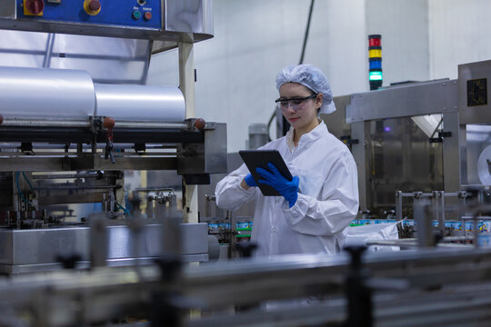 female worker inspecting pharmaceutical manufacturing process holding tablet in modern laboratory facility showing concentration and professionalism during daily operations