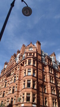 Ornate Victorian red brick building with bay windows against a blue sky