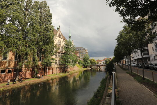 Scenic canal path with historic buildings and trees in Strasbourg, France