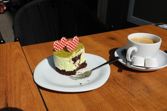 A delicious pistachio cake with red heart decorations and a cup of coffee