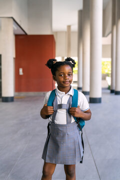 Young black student in school uniform with a backpack, ready for her first day back to school. Childhood education concept