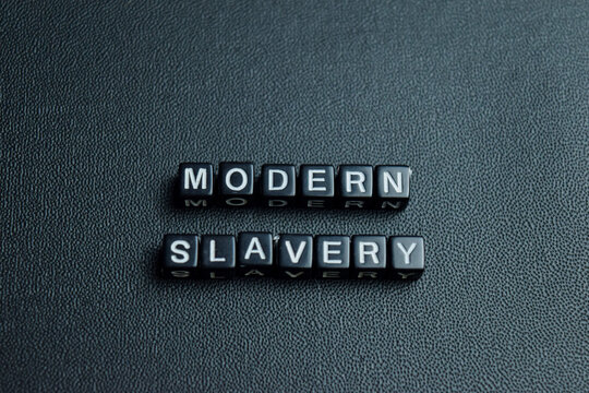 Modern slavery text stacked wooden cubes on the table. For human exploitation and global injustice
