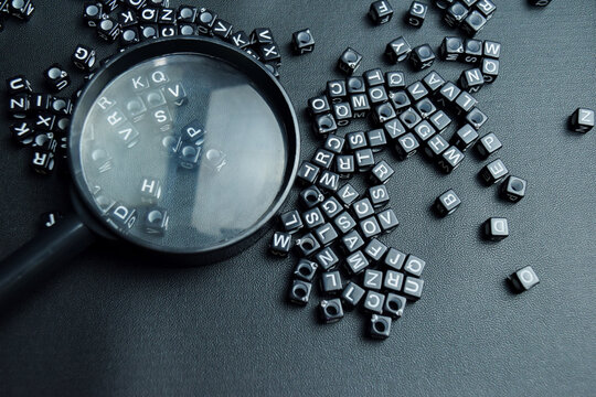 magnifying glass and stacked wooden cubes on the table. For playing scrabble will expand your vocabulary and improve skills
