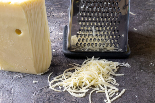Grated Cheese with Cheese Grater on Dark Surface