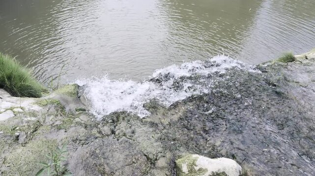 Inquadratura dall'alto del salto d'acqua che si riversa spumeggiante nel calmo bacino del fiume Metauro, presso la Cascata del Sasso