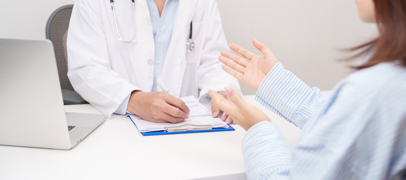 Doctor and patient having a medical consultation in a hospital room, explaining a treatment plan, discussing diagnosis, and giving advice during a medical health checkup appointment in a clinic