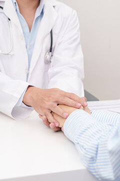 professional doctor holding patient hand to comfort, support, and give reassurance with empathy during a medical consultation and health checkup appointment, focusing on mental health in a clinic