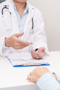 Doctor and patient having a medical consultation in a hospital room, explaining a treatment plan, discussing diagnosis, and giving advice during a medical health checkup appointment in a clinic
