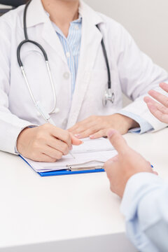 Doctor and patient having a medical consultation in a hospital room, explaining a treatment plan, discussing diagnosis, and giving advice during a medical health checkup appointment in a clinic