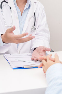 Doctor and patient having a medical consultation in a hospital room, explaining a treatment plan, discussing diagnosis, and giving advice during a medical health checkup appointment in a clinic