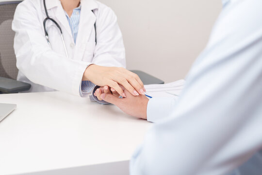 professional doctor holding patient hand to comfort, support, and give reassurance with empathy during a medical consultation and health checkup appointment, focusing on mental health in a clinic