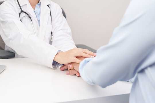 professional doctor holding patient hand to comfort, support, and give reassurance with empathy during a medical consultation and health checkup appointment, focusing on mental health in a clinic