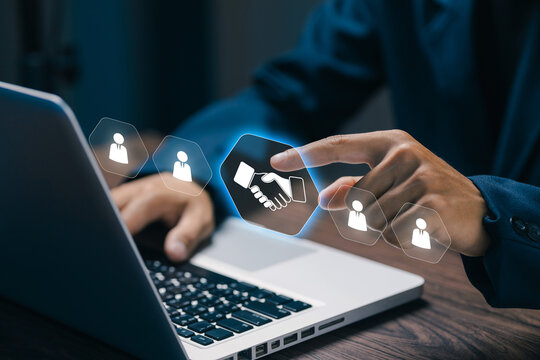 Business professional selects virtual handshake icon on laptop, representing partnership, agreement, teamwork, recruitment, collaboration, networking, trust, success, and corporate deal.