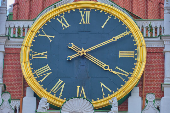 Close-up view of the historic Spasskaya Tower clock face in Moscow, Russia with golden Roman numerals and hands against a dark blue background