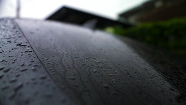 Rear view of a modern car covered in raindrops after rain. Water repellent coating, ceramic protection, auto detailing, and rainy season weather concept.