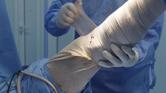 Orthopedic Surgeon Wrapping Esmarch Bandage on Patient Leg Before Surgery