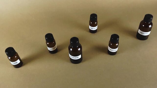 Numerous brown glass bottles containing a vaccine, a crucial element in immunization and public health campaigns, scattered across a plain background representing medical research and development