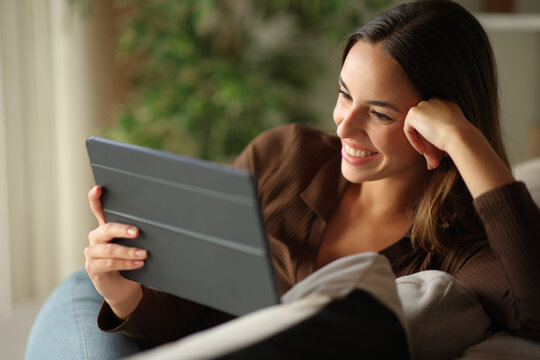 Happy woman watching online streaming conetnt on digital tablet