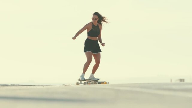 Young athletic woman skating on longboard