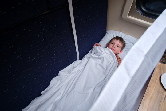 Child lying in a sleeping berth on a train. A young boy resting in a comfortable bunk bed during a long railway journey. Travel adventure and transit experience for young passenger.