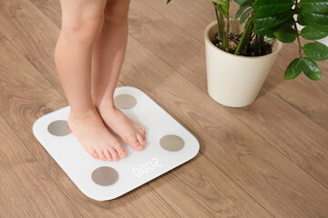 Young boy standing on digital bathroom scale at home. Child growth monitoring and healthy weight...