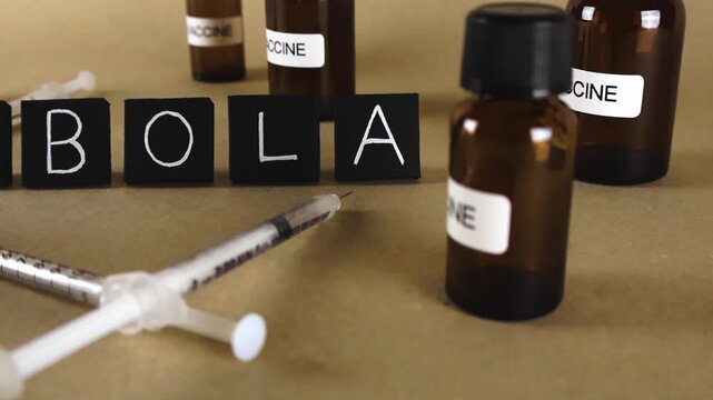 Vaccine bottles and syringes surrounding the word Ebola, representing the global effort to develop a cure and immunization for the deadly hemorrhagic fever virus disease from Africa