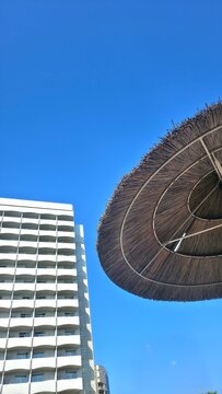 Vertical background of a modern hotel and tropical parasol, concept of vacations and tourist destinations