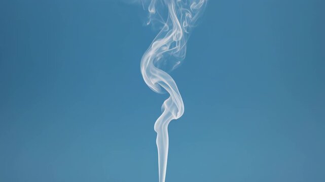White smoke plume rising with elegant swirls against a vibrant blue background during a studio shoot